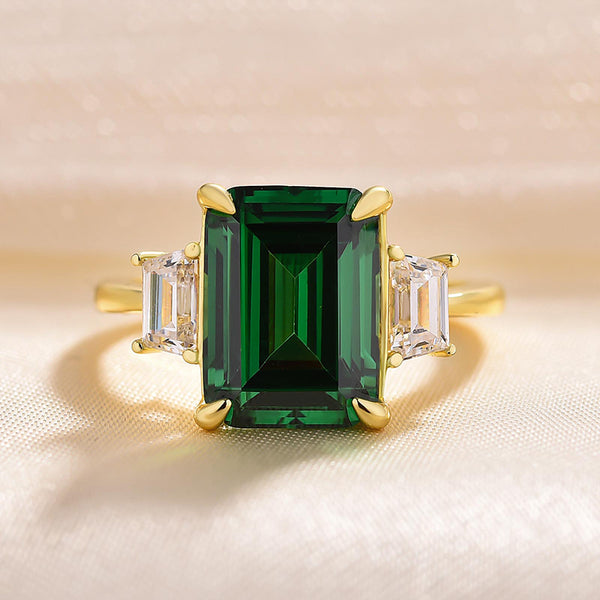 Luxurious Green Emerald Cut Three Stone Engagement Ring in Yellow Gold